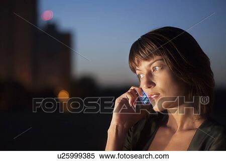 Stock Photography - Woman talks on mobile phone at night. Fotosearch