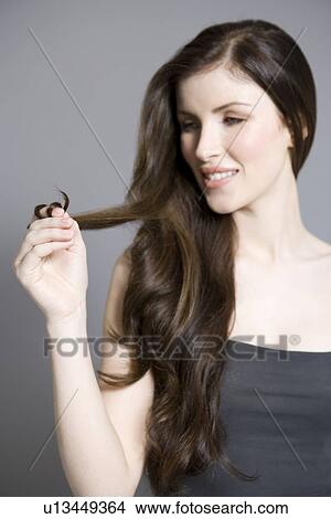 Picture - Woman twisting long brown hair. Fotosearch