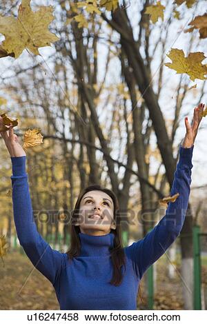 Stock Photo - Woman under falling leaves in park. Fotosearch
