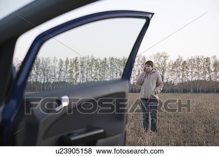 Woman using mobile phone near car in field View Large Photo Image Stock Photo - Woman using mobile phone near car in field. Fotosearch