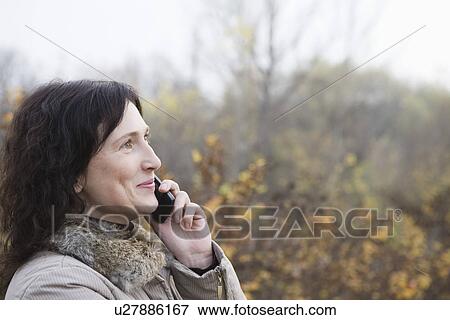Stock Photo - Woman using mobile phone outdoors. Fotosearch