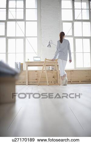 Stock Photo - Woman walks across loft apartment. Fotosearch