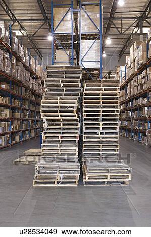 Wooden pallets stacked in distribution warehouse View Large Photo Image Stock Photo - Wooden pallets stacked in distribution warehouse. Fotosearch