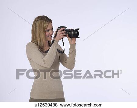 Young (20-25 years) female photographer holding camera studio shot View Large Photo Image Stock Photo - Young (20-25 years) female photographer holding camera studio shot. Fotosearch