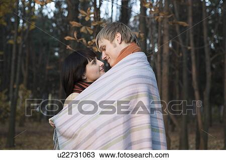 Young couple wrapped in blanket embracing in forest View Large Photo Image Stock Image - Young couple wrapped in blanket embracing in forest. Fotosearch