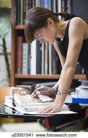 Young designer leans forward researching a book View Large Photo Image Stock Image - Young designer leans forward researching a book. Fotosearch