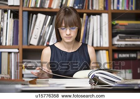 Stock Photo - Young designer sits researching in library. Fotosearch