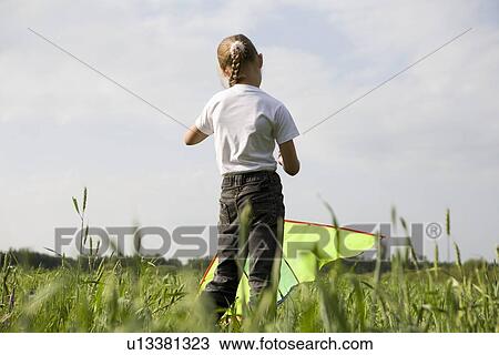 Young girl flying kite in field View Large Photo Image Stock Image - Young girl flying kite in field. Fotosearch