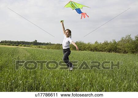 Young girl flying kite in field View Large Photo Image Stock Image - Young girl flying kite in field. Fotosearch