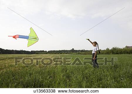 Young girl flying kite in field View Large Photo Image Stock Photo - Young girl flying kite in field. Fotosearch