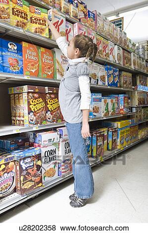 Stock Photo - Young girl reaching for ceral product in supermarket aisle. Fotosearch