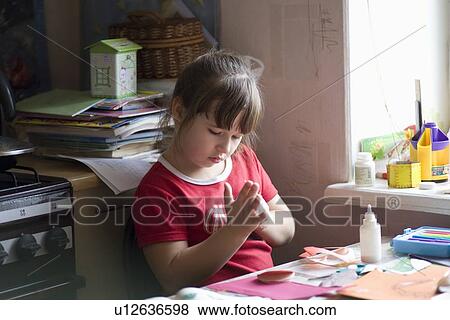 Young girl sits picking glue from her hands at workdesk View Large Photo Image Stock Photo - Young girl sits picking glue from her hands at workdesk. Fotosearch