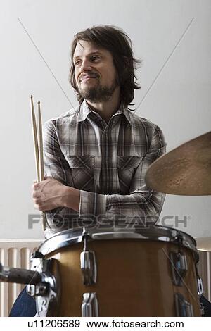 Young man sits at drumset with arms crossed holding drumsticks View Large Photo Image Stock Photo - Young man sits at drumset with arms crossed holding drumsticks. Fotosearch