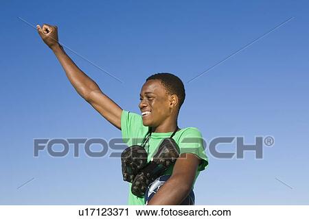 Young man with football boots round his neck and one arm raised in a fist View Large Photo Image Stock Image - Young man with football boots round his neck and one arm raised in a fist. Fotosearch