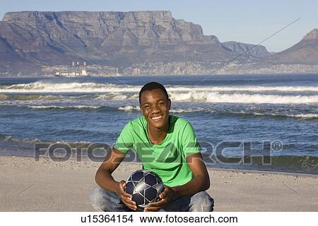 Young man with football on Table Mountain beach View Large Photo Image Picture - Young man with football on Table Mountain beach. Fotosearch