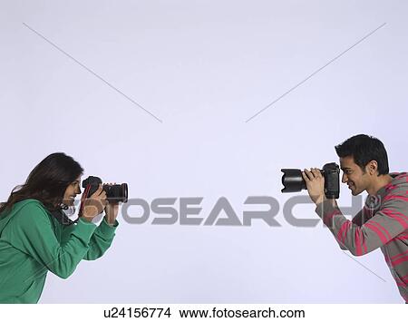 Young woman and young man photographing each other studio shot View Large Photo Image Picture - Young woman and young man photographing each other studio shot. Fotosearch