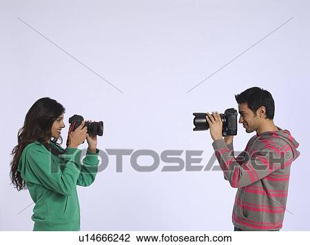 Young woman and young man photographing each other studio shot View Large Photo Image Stock Image - Young woman and young man photographing each other studio shot. Fotosearch