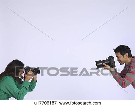 Young woman and young man photographing each other studio shot View Large Photo Image Stock Photo - Young woman and young man photographing each other studio shot. Fotosearch
