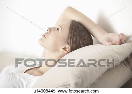 Stock Photography - Young woman lies relaxing with hand behind head. Fotosearch