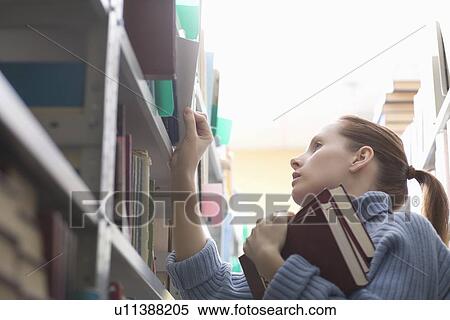 Young woman references library books on shelves View Large Photo Image Stock Photography - Young woman references library books on shelves. Fotosearch
