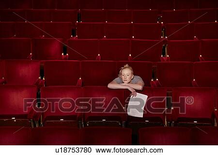 Young woman sitting in theatre stalls View Large Photo Image Stock Image - Young woman sitting in theatre stalls. Fotosearch