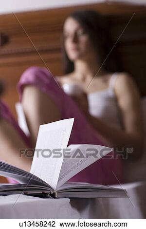 Young woman sitting on bed and reading book portrait View Large Photo Image Stock Image - Young woman sitting on bed and reading book portrait. Fotosearch