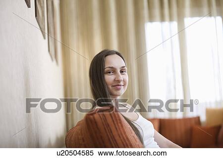 Stock Photography - Young woman sitting on sofa portrait. Fotosearch