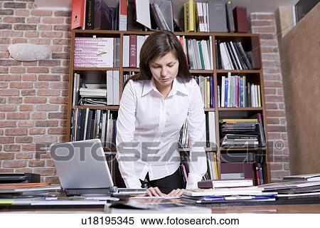 Young woman stands leaning on desk View Large Photo Image Stock Photography - Young woman stands leaning on desk. Fotosearch