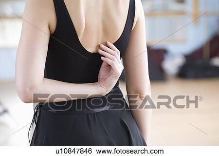 Stock Photograph - Young woman stretches in ballet rehearsal. Fotosearch