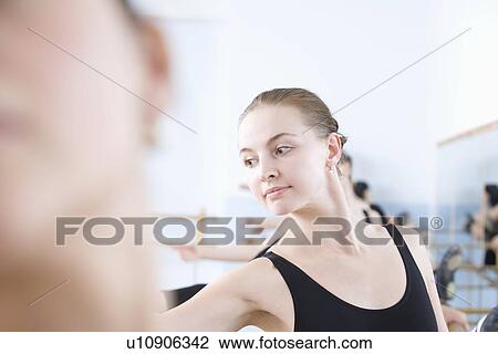 Stock Image - Young woman stretches into ballet pose. Fotosearch