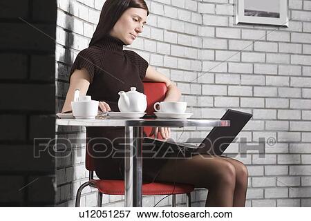 Stock Photo - Young woman using laptop in cafe. Fotosearch