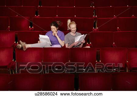 Picture - Young women sitting in theatre stalls. Fotosearch