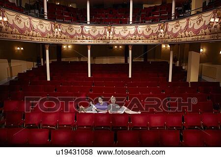 Young women sitting in theatre stalls View Large Photo Image Stock Photo - Young women sitting in theatre stalls. Fotosearch