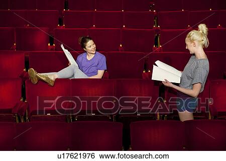 Young women sitting in theatre stalls View Large Photo Image Stock Photograph - Young women sitting in theatre stalls. Fotosearch