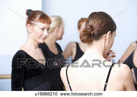 Stock Image - Young women stand in ballet rehearsal room. Fotosearch