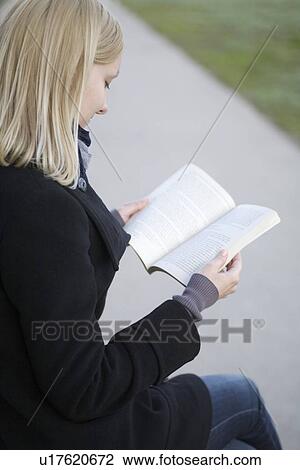 Blonde woman sits reading book outside on path View Large Photo Image Stock Image - Blonde woman sits reading book outside on path. Fotosearch