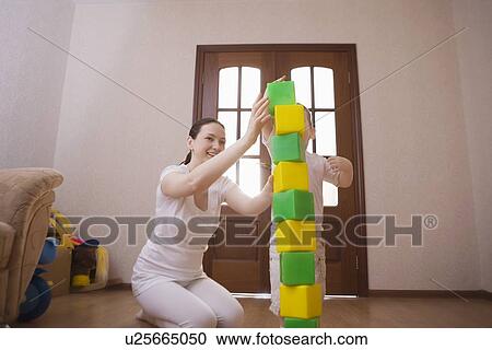 Mother and son build tower with green and yellow building blocks View Large Photo Image Stock Image - Mother and son build tower with green and yellow building blocks. Fotosearch