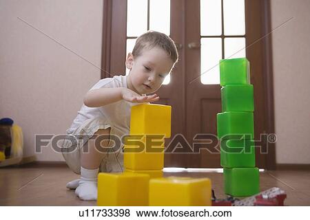 Stock Photo - Young boy plays with green and yellow building bricks. Fotosearch