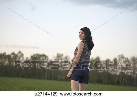 Stock Photo - Young woman in shorts walks towards woodland. Fotosearch
