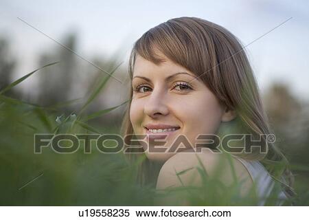 Stock Photography - Young woman lies in a field of grass. Fotosearch