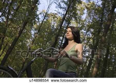 Young woman stands with bicycle in woodland View Large Photo Image Picture - Young woman stands with bicycle in woodland. Fotosearch