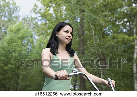 Young woman stands with bicycle in woodland View Large Photo Image Stock Photograph - Young woman stands with bicycle in woodland. Fotosearch