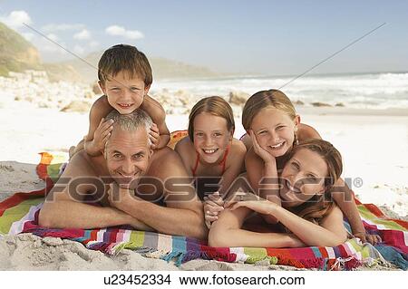 Picture - Family lying on beach.. Fotosearch