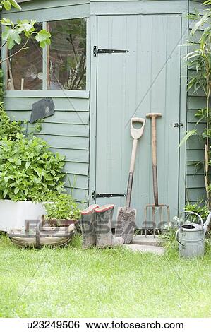 Stock Photograph - Gardening tools lean against door of potting shed. Fotosearch