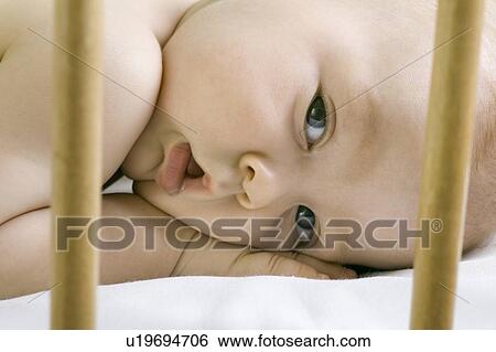 Stock Photograph - Infant child lying in cot. Fotosearch