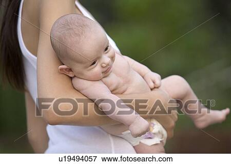 Stock Photo - Mother stands holding 2 month old infant son. Fotosearch