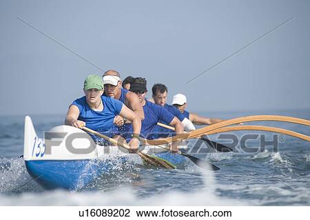 Stock Image - Outrigger canoeing team on water. Fotosearch