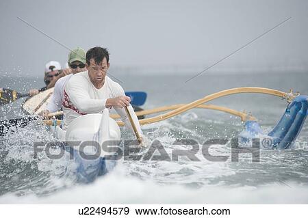 Stock Photo - Outrigger canoeing team on water. Fotosearch