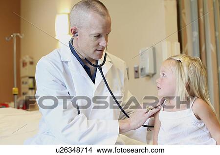 Picture - Young pediatrician listens to young girl's breathing. Fotosearch