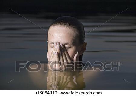 Stock Photo - Young woman covers her face with her hands in water. Fotosearch